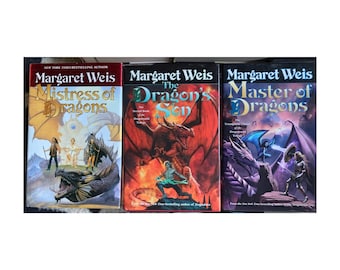 May include: Three fantasy novels by Margaret Weis are displayed. The titles are "Mistress of Dragons", "The Dragon's Son", and "Master of Dragons". The covers feature dragons, warriors, and fantasy scenes in shades of red, blue, and gold.
