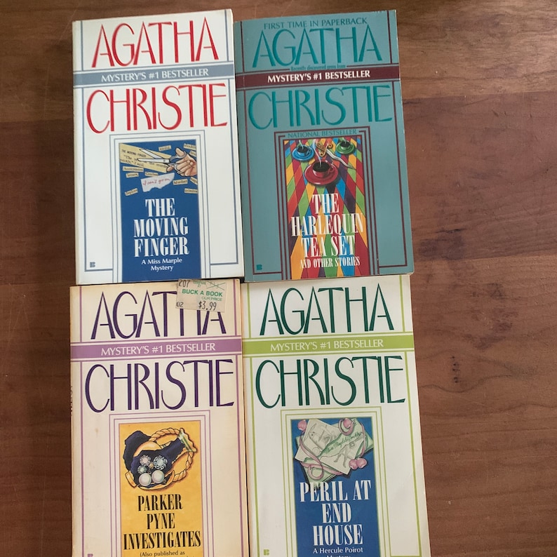 May include: Four paperback books by Agatha Christie, all featuring the author's name and the words "Mystery's #1 Bestseller" on the cover. The titles are "The Moving Finger", "The Harlequin Tea Set", "Parker Pyne Investigates", and "Peril at End House".