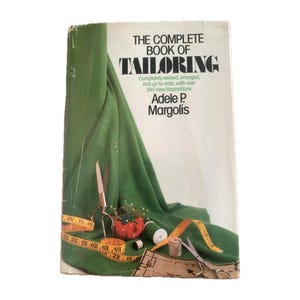 May include: The Complete Book of Tailoring by Adele P. Margolis. The book cover features a green fabric draped over a white background with sewing supplies, including scissors, needles, thread, and measuring tape.