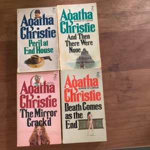 May include: Four paperback books by Agatha Christie. The titles are "Peril at End House", "And Then There Were None", "The Mirror Crack'd", and "Death Comes as the End".