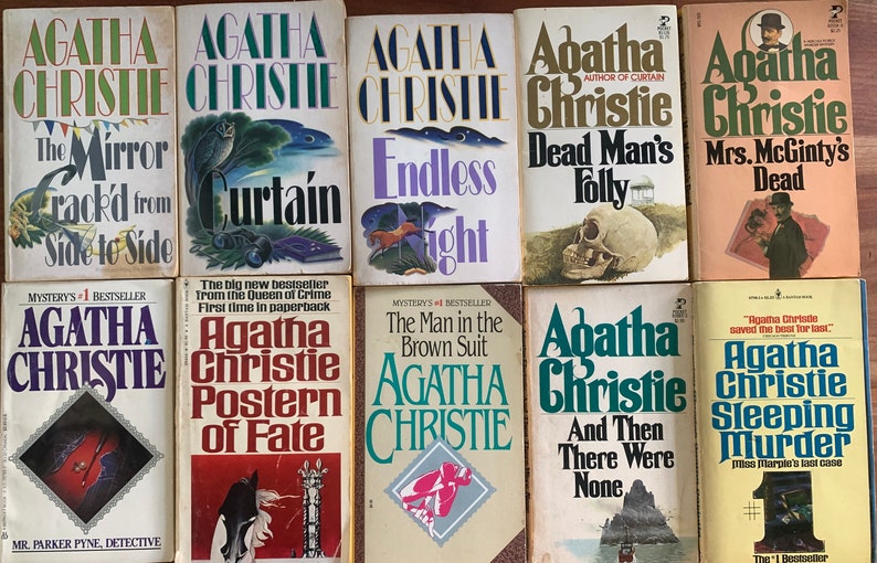 May include: A collection of ten paperback mystery novels by Agatha Christie. The books feature colorful covers with illustrations and titles such as "The Mirror Crack'd from Side to Side", "Curtain", "Endless Night", "Dead Man's Folly", "Mrs. McGinty's Dead", "Postern of Fate", "The Man in the Brown Suit", "And Then There Were None", and "Sleeping Murder".