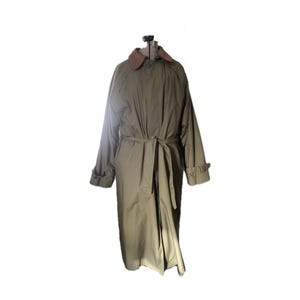May include: A long, olive green trench coat with a brown collar and a belt. The coat has a classic design and is perfect for layering in colder weather.