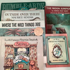 May include: A stack of children's books by Maurice Sendak, including "Where the Wild Things Are", "Outside Over There", and "Chicken Soup with Rice: A Book of Months".
