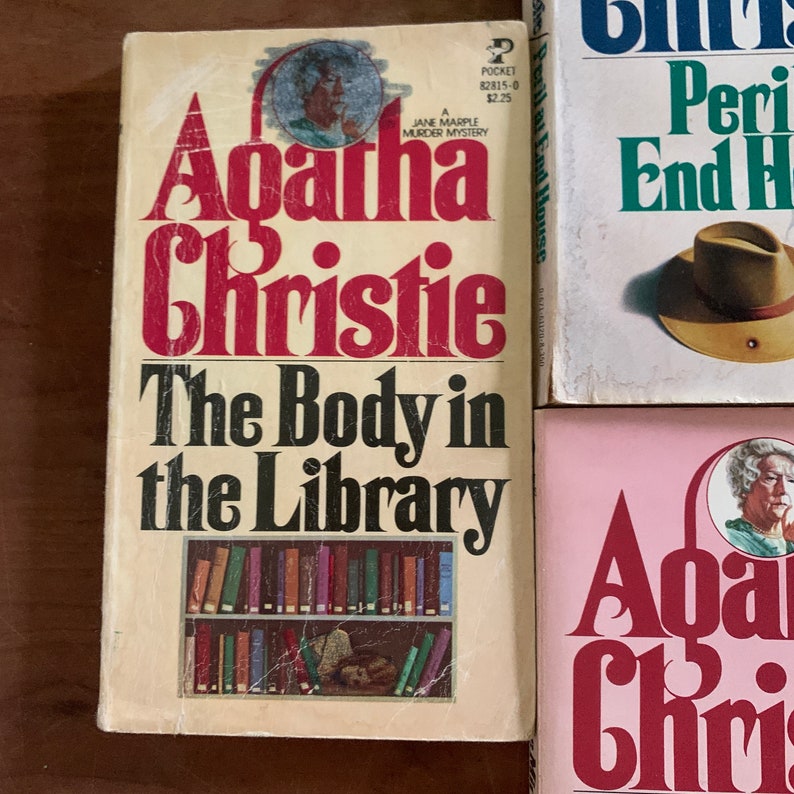 May include: Three paperback books by Agatha Christie. The first book is "The Body in the Library", the second is "Peril at End House", and the third is "The Mirror Crack'd from Side to Side".