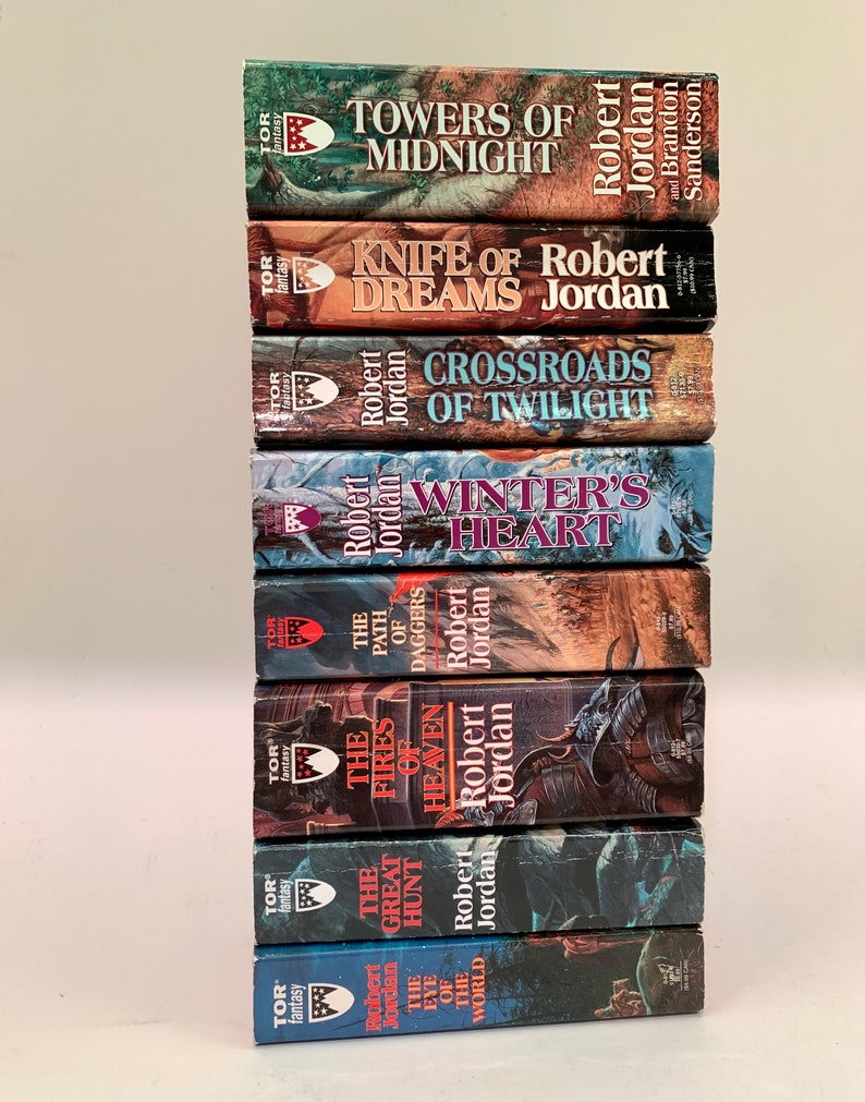 Pu&ograve; includere: Una pila di dieci romanzi fantasy in brossura di Robert Jordan, intitolati "L'occhio del mondo", "La grande caccia", "I fuochi del cielo", "Il sentiero delle daghe", "Il cuore d'inverno", "Crocevia del crepuscolo", "Il coltello dei sogni", "Torri di mezzanotte", e "La ruota del tempo".