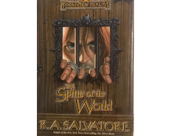 May include: A hardcover book titled "The Spine of the World" by R.A. Salvatore. The cover features a man behind bars, with the text "Forgotten Realms" at the top. The book is a sequel to "The Silent Blade".