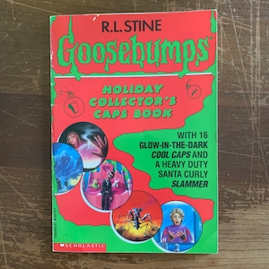 May include: A vintage "Goosebumps" book titled "Holiday Collector's Caps Book" by R.L. Stine. The cover is red and green with illustrations and the text "WITH 16 GLOW-IN-THE-DARK COOL CAPS AND A HEAVY DUTY SANTA CURLY SLAMMER".