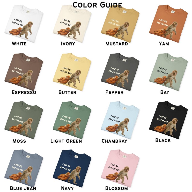 May include: A collection of t-shirts in various colors, each featuring a graphic of a cartoon-like creature and the text "I ACT OK, BUT I'M NOT." Colors include white, ivory, mustard, yam, espresso, butter, pepper, bay, moss, light green, chambray, black, blue jean, navy, and blossom.