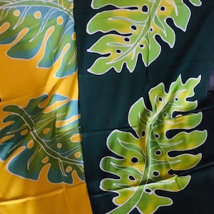 May include: Two fabric panels with a tropical leaf pattern. One panel is yellow with blue and green accents, the other is dark green with light green and white accents. The leaves have a detailed, stylized design.