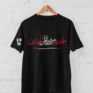 K&ouml;nnte beinhalten: Schwarzes T-Shirt mit roter und wei&szlig;er arabischer Kalligraphie und dem englischen Text "Hussain is from me, and I am from Hussain." Das Shirt hat auch ein Logo auf dem linken &Auml;rmel.