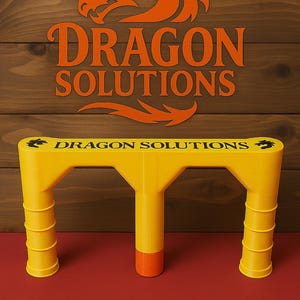 May include: A yellow, three-legged structure with the text "DRAGON SOLUTIONS" printed on it. The structure has an orange base and is set against a red surface and a wooden background with the "DRAGON SOLUTIONS" logo.