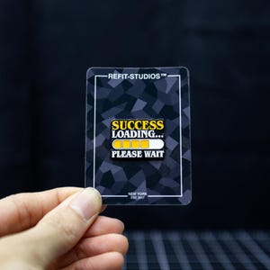 May include: A rectangular pin with a black and gray geometric pattern background. The pin features the text "SUCCESS LOADING..." with a loading bar graphic and "PLEASE WAIT" below. The text "REFIT-STUDIOS" and "NEW YORK EST. 2017" are also visible.