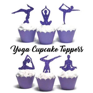 May include: Purple glitter yoga cupcake toppers. The toppers feature different yoga poses, including downward dog, warrior one, and lotus pose. The toppers are on top of purple cupcake liners.