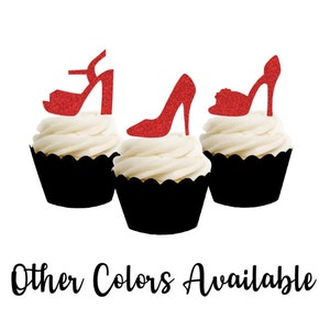 May include: Three cupcakes decorated with red glitter shoe toppers. The cupcakes are frosted with white frosting and have black cupcake liners. The text "Other Colors Available" is written below the cupcakes.