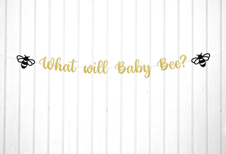 May include: Gold glitter banner with the text "What will Baby Bee?" and black bee silhouettes on each end.