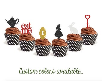 May include: Six chocolate cupcakes with black and white polka dot liners. Each cupcake is topped with a different glitter-covered topper: a teapot, the words "eat me", a keyhole, Alice in Wonderland, a white rabbit, and a red heart key.