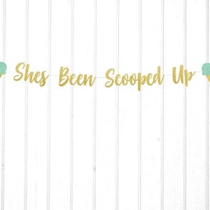 Puede incluir: Pancarta de purpurina dorada con el texto "She's Been Scooped Up" y dos recortes de conos de helado verde y blanco.