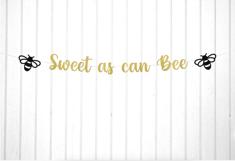 May include: Gold glitter banner with the text "Sweet as can Bee" and two black bee silhouettes on either end.