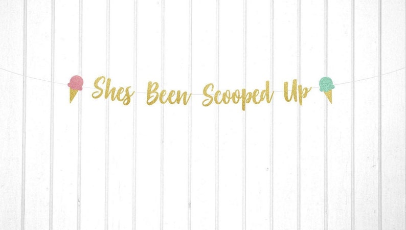 Puede incluir: Pancarta de purpurina dorada con el texto "She's Been Scooped Up" y dos recortes de conos de helado, uno rosa y otro verde.