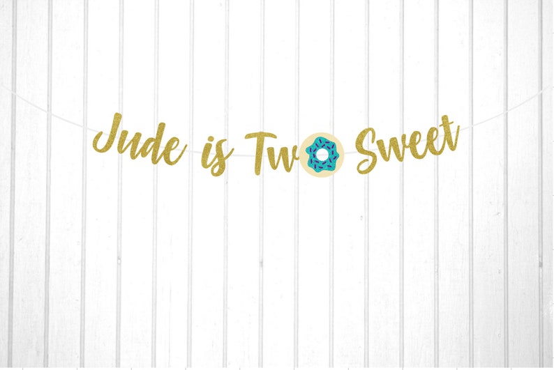 Puede incluir: Pancarta de brillo dorado con el texto "Jude is Two Sweet" y un gr&aacute;fico de donut azul y blanco.
