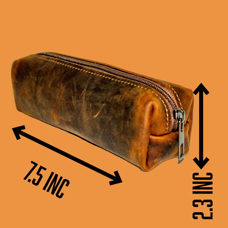May include: A brown leather pencil case with a zipper closure. The case is 7.5 inches long and 2.3 inches high. The leather has a distressed look with variations in color. The zipper is silver-colored.