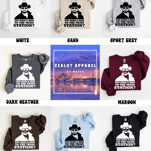 K&ouml;nnte beinhalten: Eine Auswahl an lang&auml;rmeligen Sweatshirts in verschiedenen Farben, darunter Wei&szlig;, Sand, Sportgrau, Dunkelgrau, Bordeaux, Dunkelschokolade, Hellblau und Schwarz. Jedes Sweatshirt zeigt eine Grafik eines Mannes mit Cowboyhut und dem Text "YOU NEED A RIDE TO THE TRAIN STATION?"