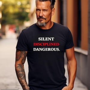 May include: Black t-shirt with the words "SILENT DISCIPLINED DANGEROUS." in white and red text. The shirt is a crew neck style. The word "BLACK" is in a gray box at the bottom left of the image.