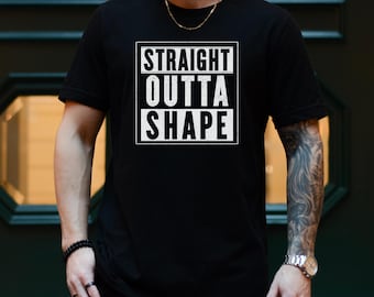 May include: Black t-shirt with the text "STRAIGHT OUTTA SHAPE" in a white, bold font within a white rectangular frame. The shirt is short-sleeved and appears to be made of a soft material. The word "BLACK" is at the bottom left of the image.