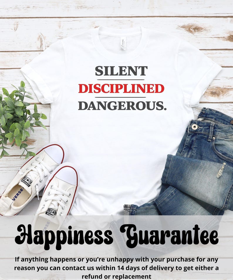 May include: White t-shirt with the words "SILENT DISCIPLINED DANGEROUS." in black and red. The shirt is paired with blue jeans and white canvas sneakers. The text "Happiness Guarantee" is also visible.