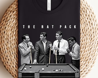 May include: A black t-shirt featuring a graphic print of The Rat Pack standing around a pool table. The design shows four men in suits, with the text THE RAT PACK printed in white above them. The shirt has a crew neckline and short sleeves.