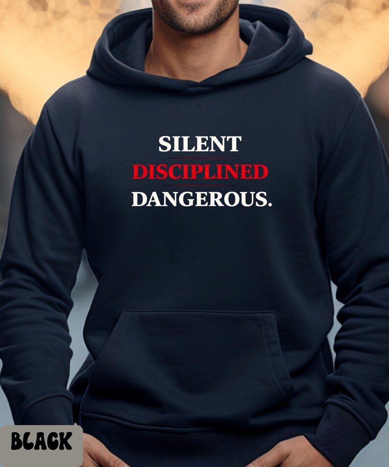 May include: A navy blue hoodie with a front pocket and the words "SILENT DISCIPLINED DANGEROUS." in white and red lettering. The word "BLACK" is at the bottom left corner of the image.