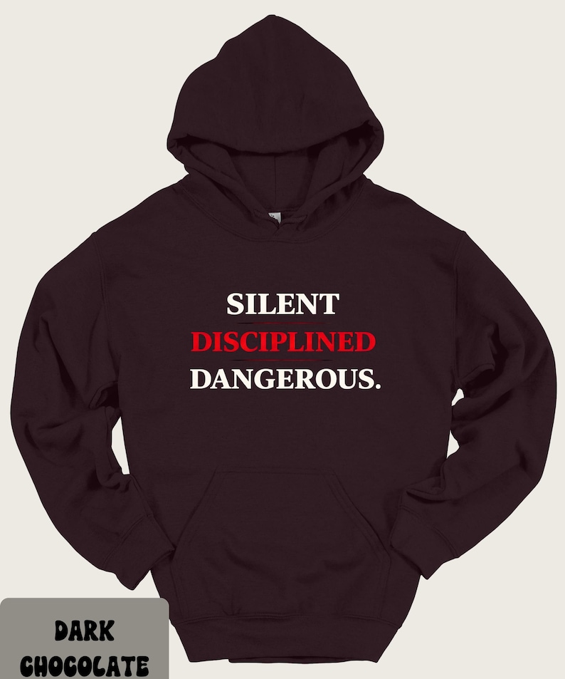 May include: Dark chocolate-colored hoodie with a front pocket and hood. The text "SILENT DISCIPLINED DANGEROUS" is printed in white and red. The bottom left corner of the image has the text "DARK CHOCOLATE".