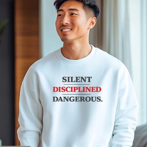 May include: White crew neck sweatshirt with the words "SILENT DISCIPLINED DANGEROUS." printed in black and red. The word "WHITE" is printed in a white box at the bottom left of the image.