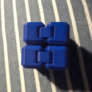 May include: A blue fidget toy with a square shape and a hinged design. The toy is made of plastic and has a smooth surface.