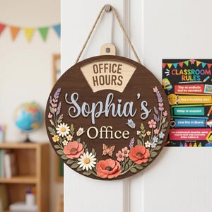May include: A round wooden door sign with a dark brown finish, featuring the text "OFFICE HOURS" at the top and "Sophia's Office" in the center. The sign is decorated with layered, colorful floral cutouts and butterflies, suspended by a jute rope.
