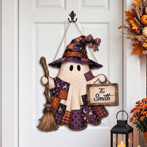 May include: A hanging ghost decoration featuring a purple and orange patchwork witch hat and body, holding a wooden broomstick and a rectangular sign that reads The Smith. The design includes star, moon, and potion bottle patterns.