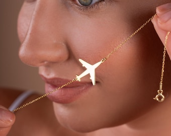 Op de afbeelding: Een gouden ketting met een delicate vliegtuighanger. De hanger is een eenvoudige silhouet van een vliegtuig, zonder details.