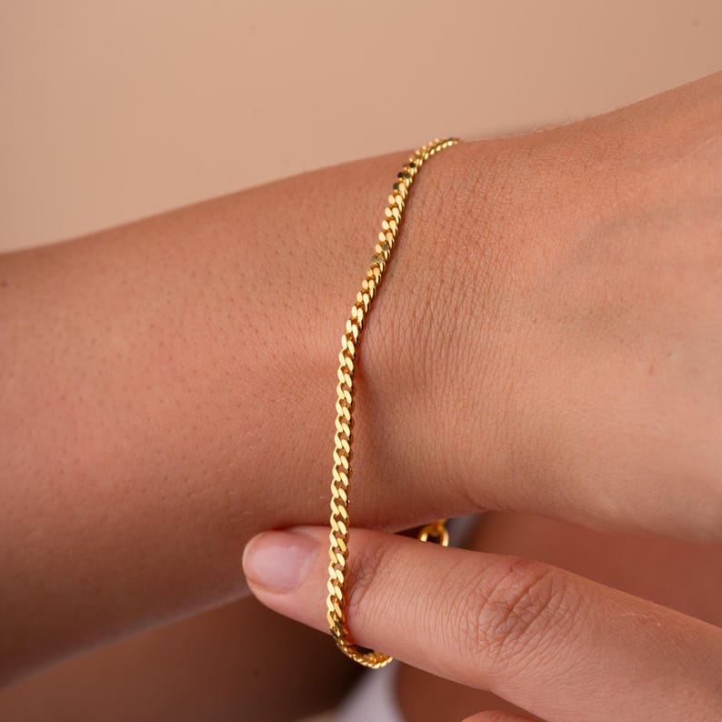Op de afbeelding: Een gouden kettingarmband met een curb-link ontwerp.