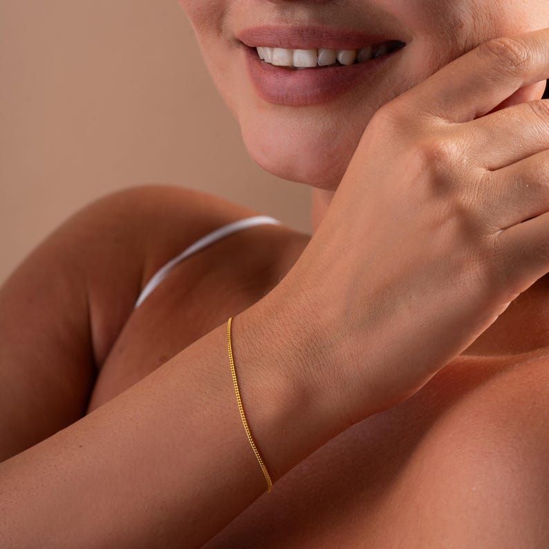 Op de afbeelding: Een delicate gouden kettingarmband met een eenvoudig ontwerp.