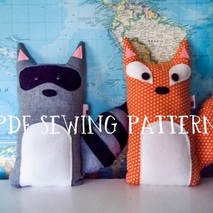 May include: A PDF sewing pattern for making plush toys. The pattern includes instructions for making a raccoon and a fox. The raccoon is gray with black eyes and a white belly. The fox is orange with white eyes and a white belly. The pattern is printed on a white background.