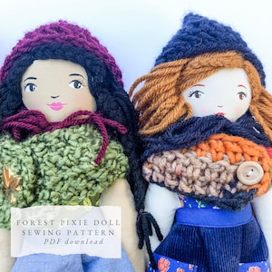 May include: Two handmade fabric dolls featuring embroidered facial features and yarn hair. The left doll wears a purple knit hood and green textured cape. The right doll wears a dark blue knit hood and a multi-colored scarf with a button. Text reads: FOREST PIXIE DOLL SEWING PATTERN PDF download.