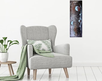 May include: Abstract art painting with blue, white, and brown colors. The painting features a vertical design with a textured surface. The painting is hanging on a white wall in a living room setting.