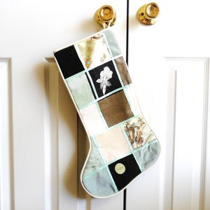 May include: A patchwork Christmas stocking with a white background and various colored fabric squares. The stocking is decorated with a floral design and a dragon pattern.