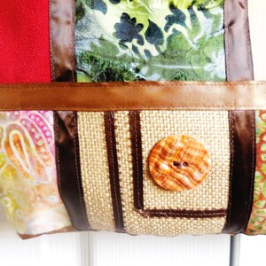 May include: A patchwork tote bag with a brown, beige, and green fabric design. The bag has a brown button and a brown ribbon.