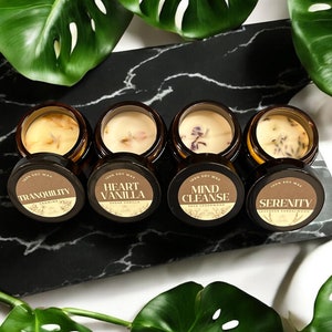 Pu&ograve; includere: Cinque piccoli barattoli di vetro con coperchi marroni che contengono candele di cera di soia. Le etichette sui barattoli recitano "Tranquility", "Heart Vanilla", "Mind Cleanse", "Serenity" e "Tranquility".