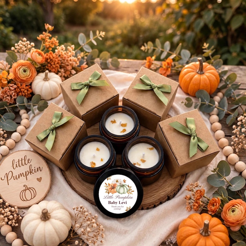 May include: Four brown cardboard gift boxes with green ribbon bows, three amber glass jars containing white candles with wax embeds, and one black candle lid featuring a floral pumpkin graphic and the text Little Pumpkin Baby Levi.