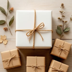 May include: Five wrapped gifts, four are brown with twine bows and one is white with a twine bow. The gifts are on a light brown wooden surface with dried foliage on either side.