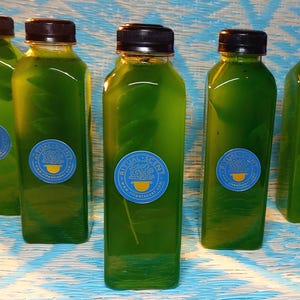 May include: Five green glass bottles with a blue and white label that says "Ritual Scent" and a picture of a teacup. The bottles are on a blue and white patterned surface.