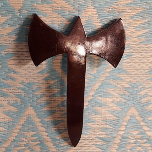 May include: A black double-headed axe with a pointed blade. The axe is made of wood and has a smooth, polished finish.