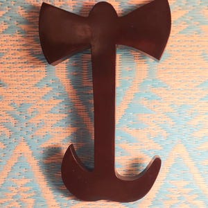 May include: A dark brown wooden axe-shaped bottle opener with a hook on the bottom.
